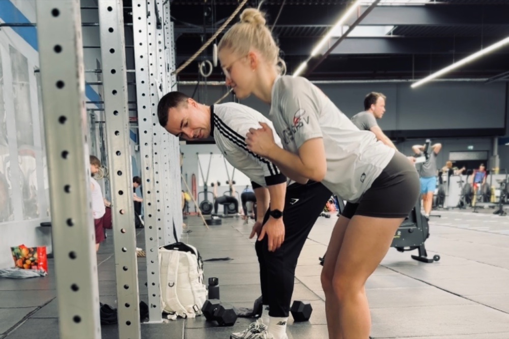 Ronnie Nolte korrigiert die Hüftbeuge-Technik einer Athletin im Kraftraum